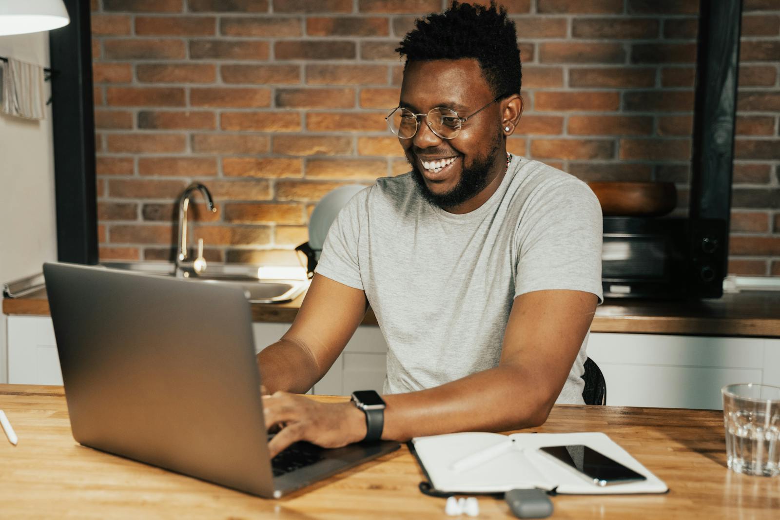 virtual assistant job in canada African American man smiling while working remotely on laptop from home office
